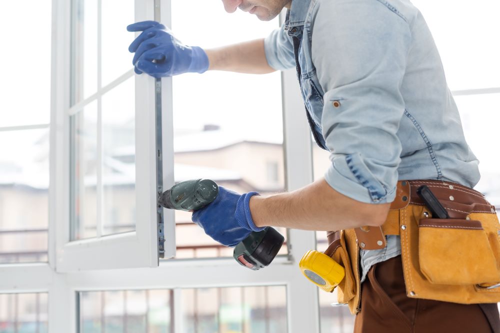 Window contractor installing a window with screwdriver